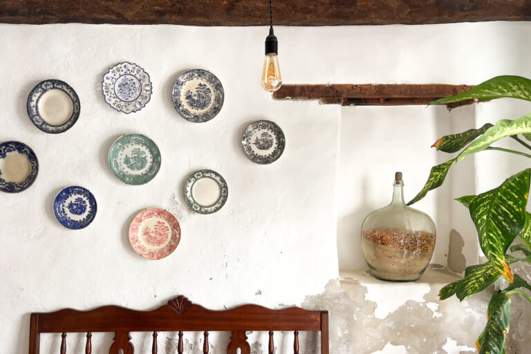 Sfeerfoto van het authentieke restaurant en museum Sodade in Sal Rei op Boa Vista, er hangen oude handgeschilderde bordjes aan de muur en er staat een pot in een nis in de muur